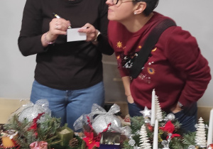 Dwie mamy przy stoisku klasy trzeciej, sprzedające stroiki i inne ozdoby.