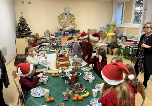 Uczniowie przy w zastawionym stole wigilijnym.