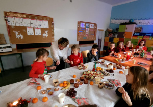 Pnia wicedyrektor i uczniowie klasy 1a dzielący się opłatkiem.