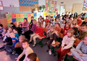 Dzieci siedzące na widowni w jednej z sal szkolnych.