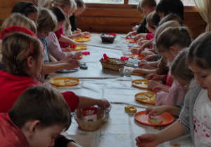 Uczniowie klas pierwszych wykrawające ciasteczka w różnych kształtach.