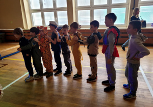 Chłopcy tworzący węża stojący jeden za dreugim.