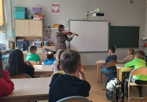 Mama jednego z uczniów grająca na skrzypcach, przed nią uczniowie klasy 3b.