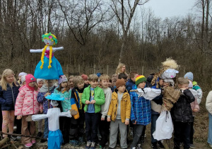 Dzieci z klas 1b i 2b stojące przy ognisku ze swoimi Marzannami