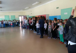 Dzieci zebrane na apelu stoja klasami w okręgu.