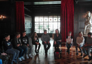 Dzieci siedzące w kręgu podczas warsztatów pt. "Pałacowe maniery", w jednej z sal willi Herbsta.