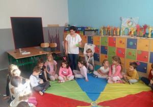 Na zdjęciu dzieci siedzące na kolorowej chuście animacyjnej w trakcie zabawy.