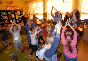 Dzieci z uniesionymi ku górze rękami, naśladujące w rytm muzyki start i lot rakiety.