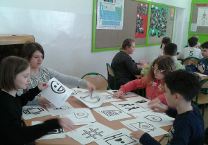 Uczniowie pracujący w grupach, przyglądają się symbolom umieszczonym na kartach pracy.
