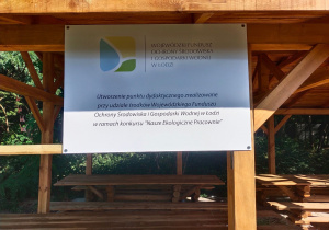 Tablica z informacyjną, że punkt dydaktyczny zrealizowany został przy udziale środków z Wojewódzkiego Funduszu Ochrony Środowiska i Gospodarki Wodnej, przytwierdzona do altany.